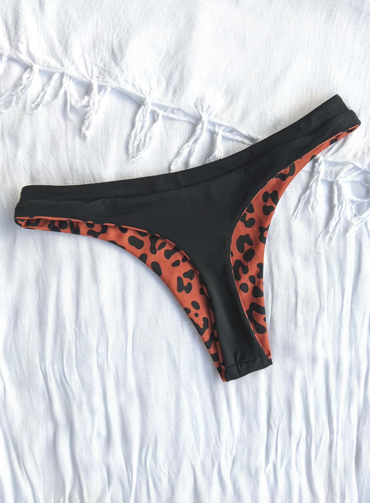 Reversible Black and Leopard Print Skimpy Cut Bikini Bottom Made From Eco Friendly Recycled Regenerated Nylon Fabric Leopard Print Back Flat Lay View